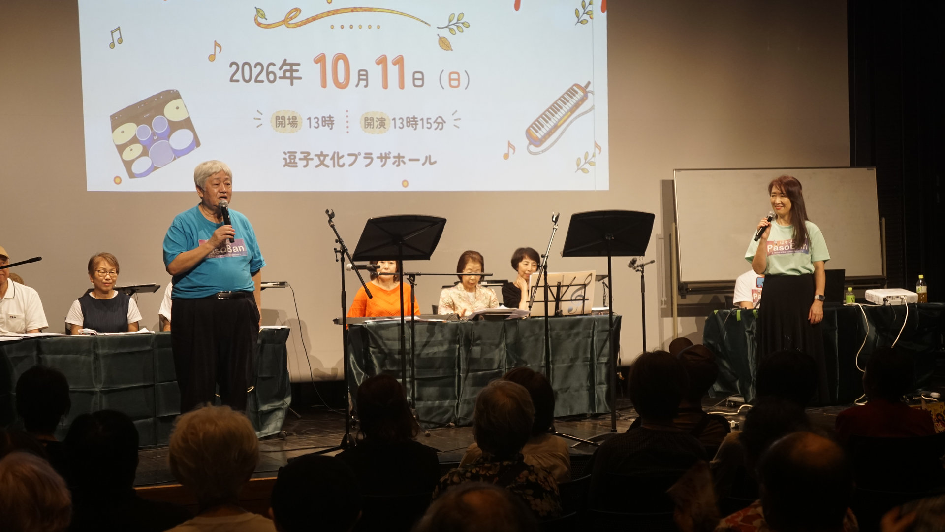 コンサート会場でマイクを持って挨拶する出演者。
